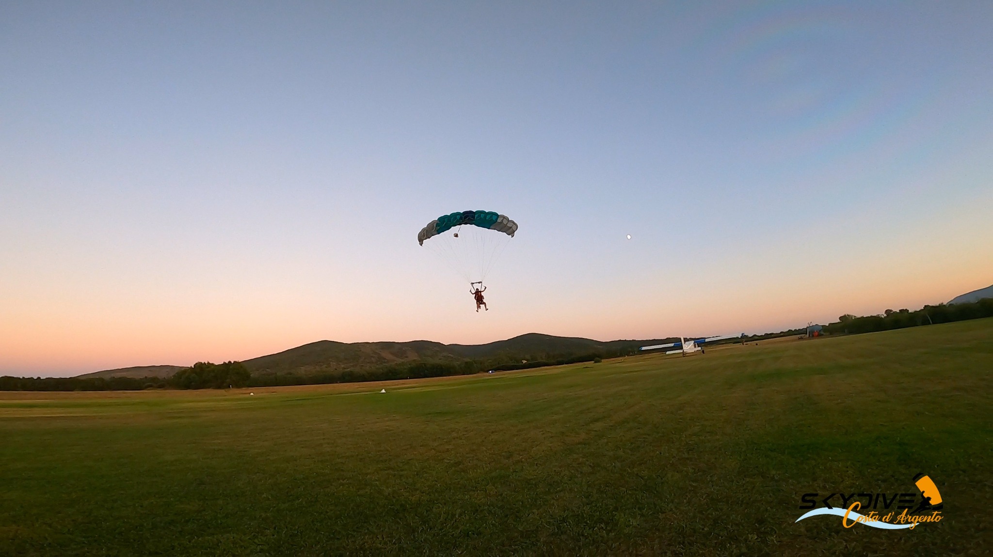 A skydiver silhouetted against the sunset over the sea
